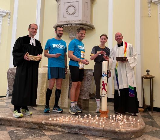 Vikar Wisssing (l.), Kaplan Dr. Christian Jasper (r.) und weitere Teilnehmende des Marathons entzündeten die Marathonkerze in der Schlosskirche.