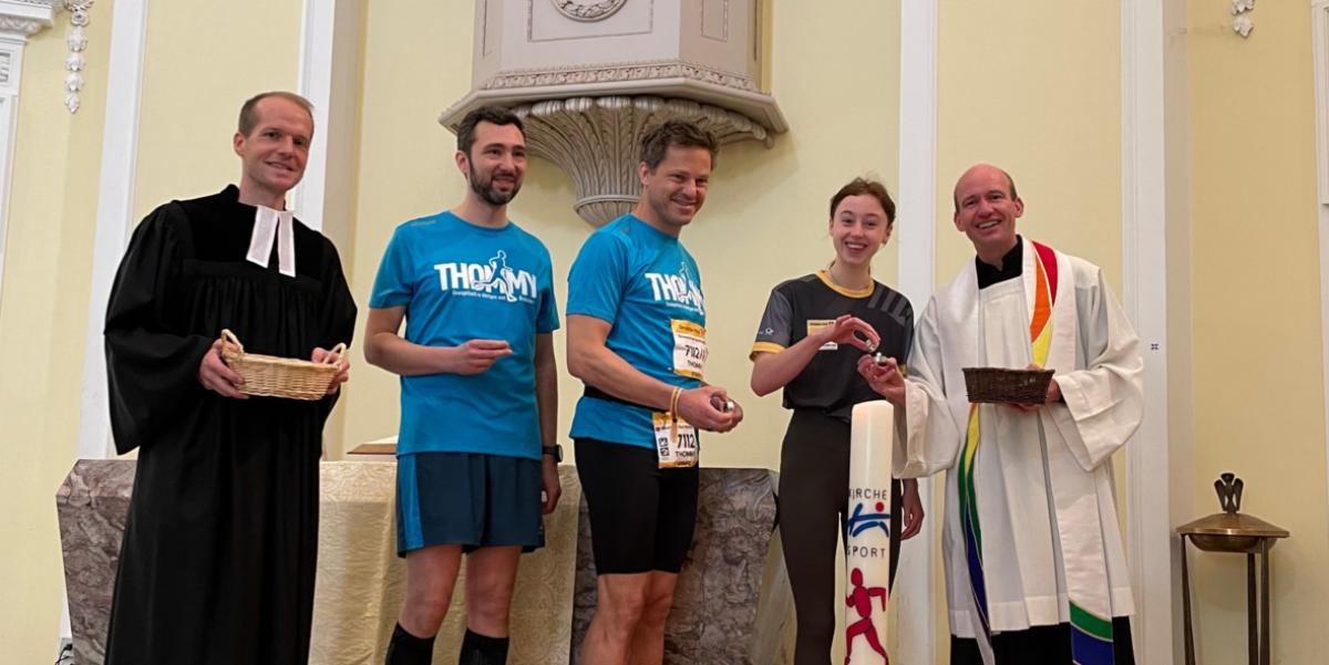 Vikar Wisssing (l.), Kaplan Dr. Christian Jasper (r.) und weitere Teilnehmende des Marathons entzündeten die Marathonkerze in der Schlosskirche.